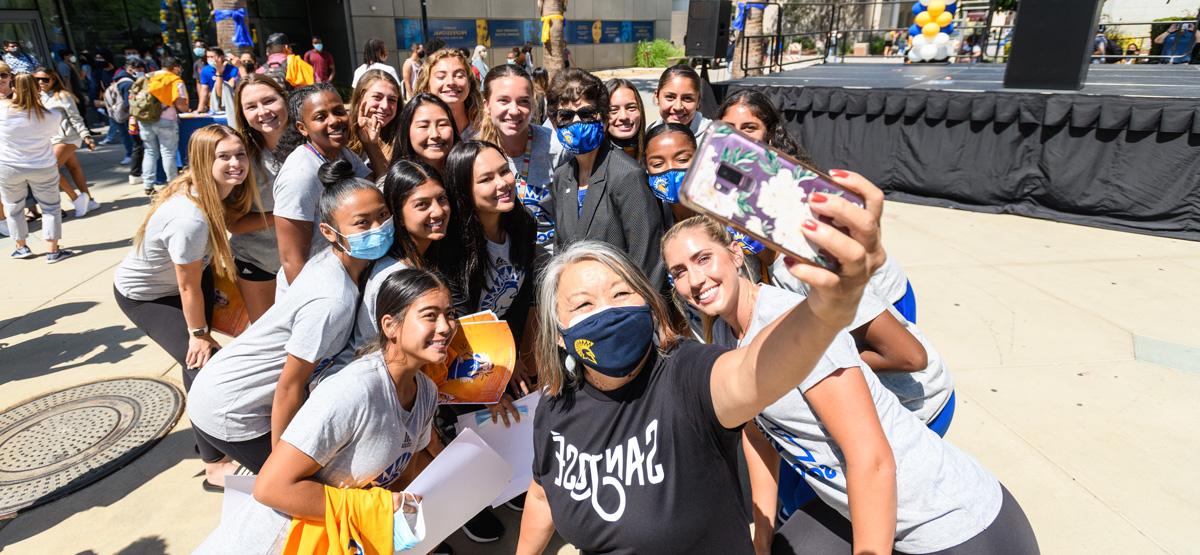 A staff member take a photo with students for social media.