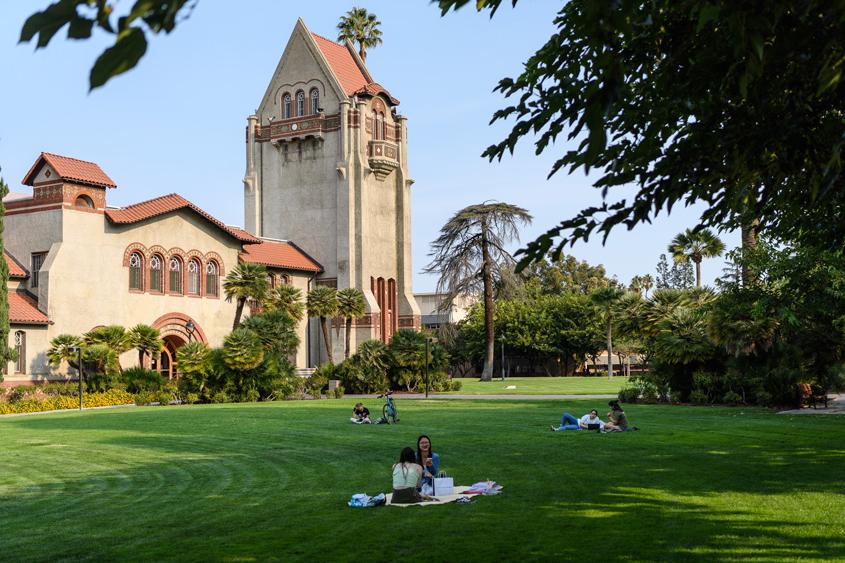 Students relaxing on the lawn by Tower Hall on campus.